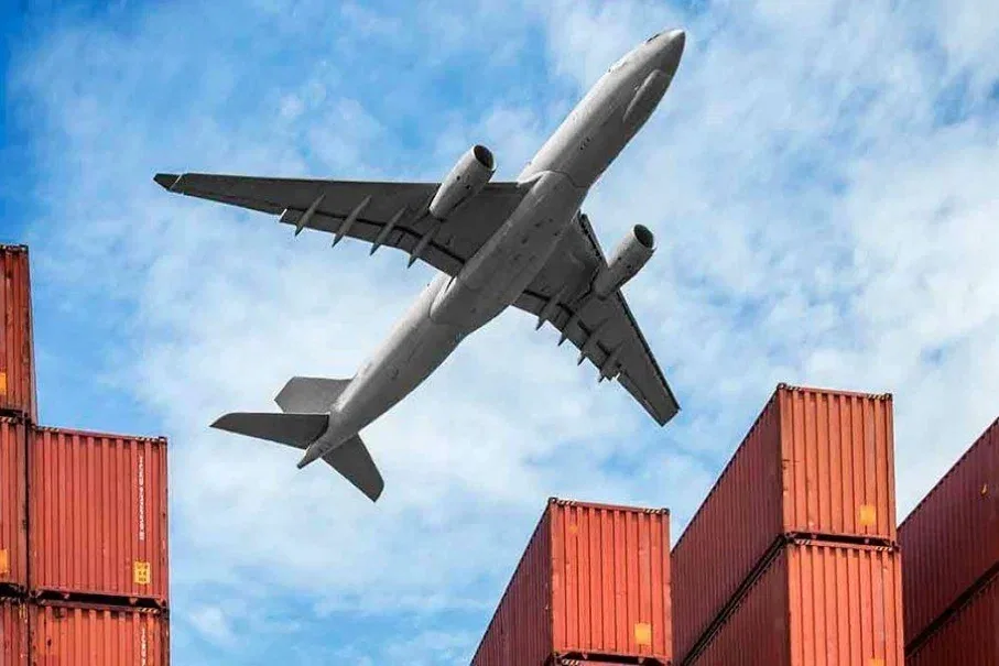 Cargo aircraft above stacked shipping containers, representing air freight for urgent orders from China